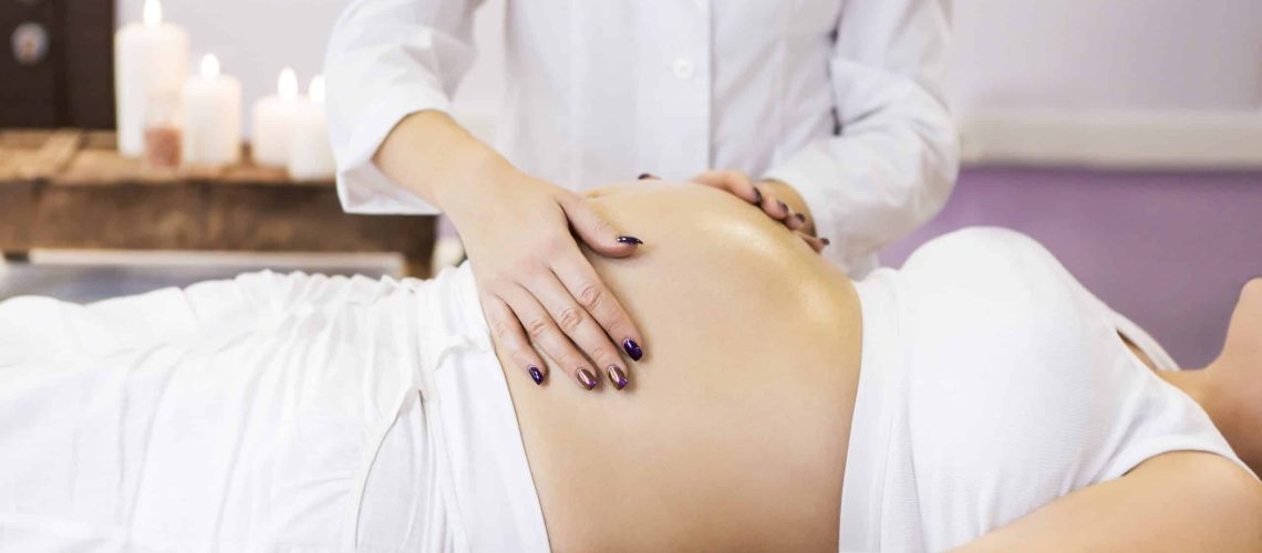 Young pregnant woman have massage treatment at spa salon