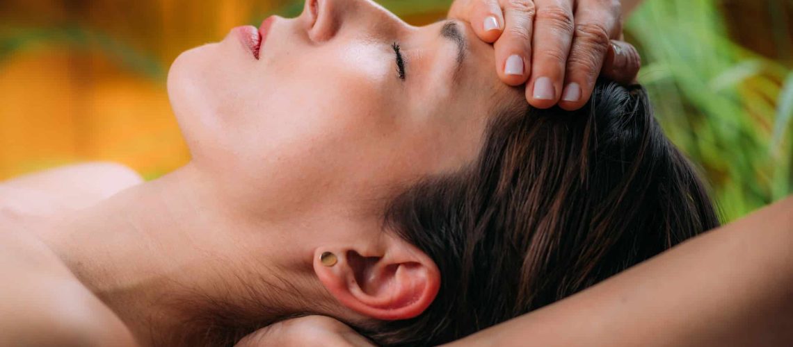 Craniosacral therapy massage. Therapist massaging woman’s forehead.